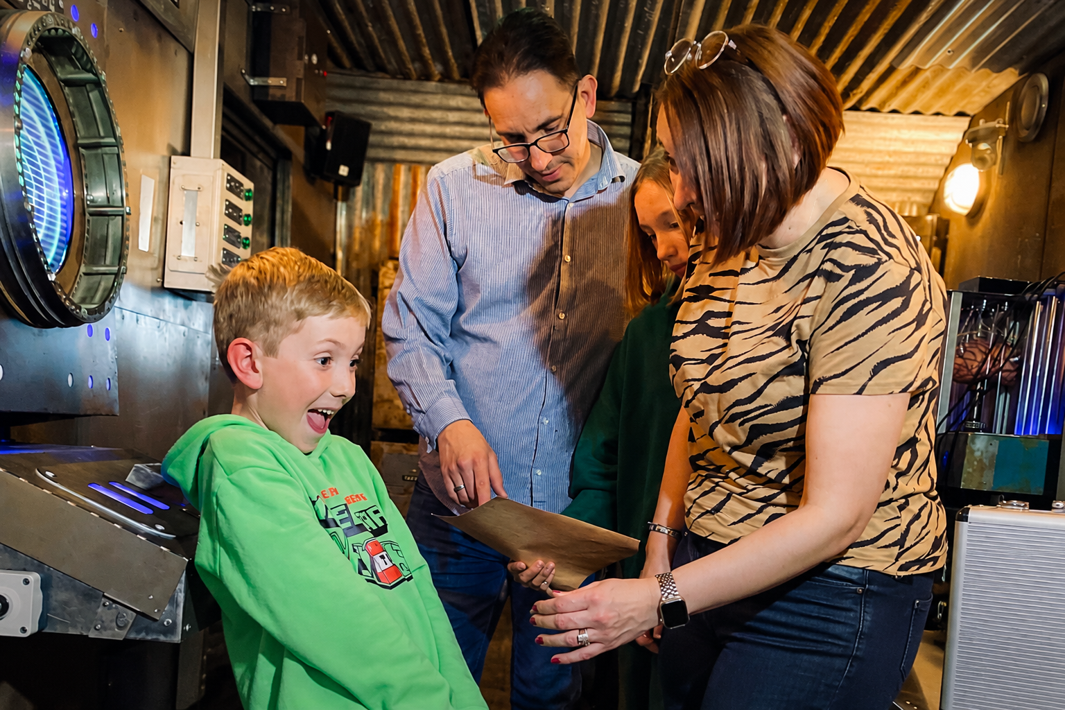 A delighted child solving a puzzle with his family at The Escapement